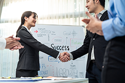 Whiteboard behind NCR dealers shaking hands 